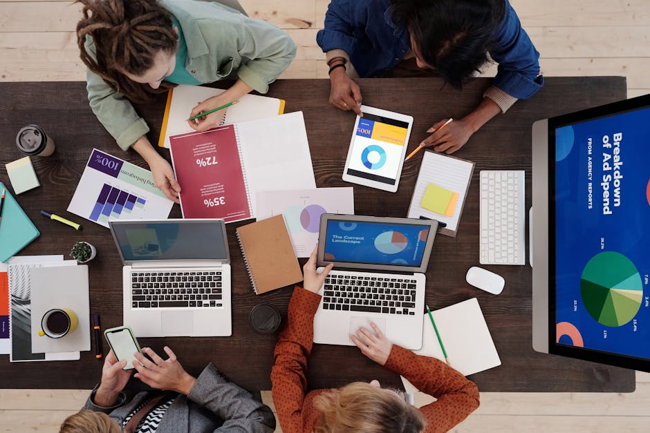 A diverse team collaborating on digital marketing strategies at a desk, using laptops and tablets
