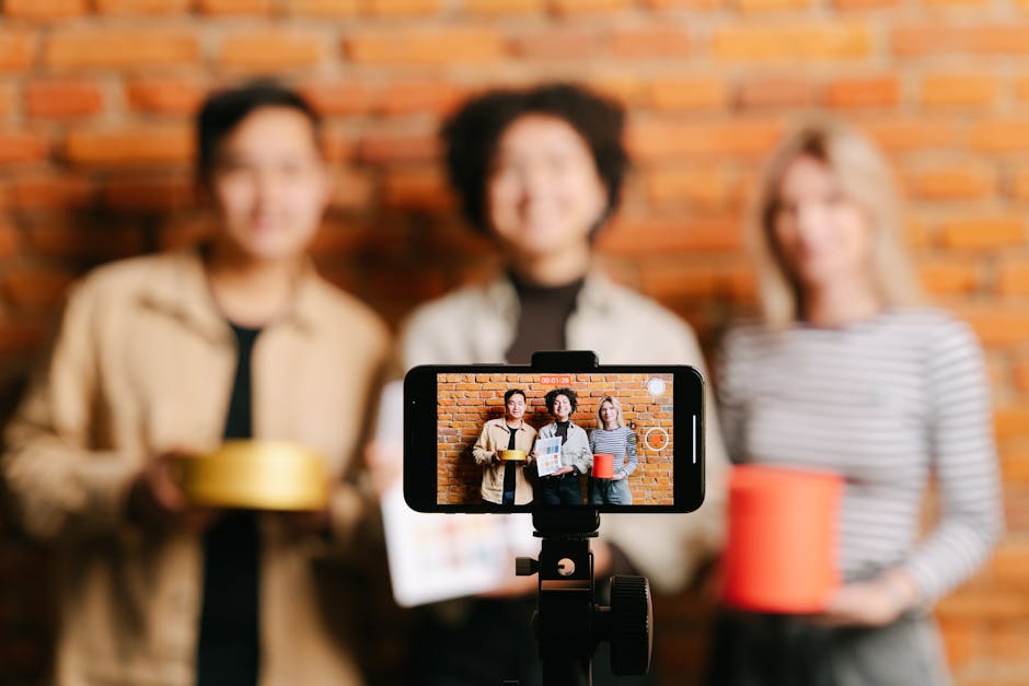 A diverse team of vloggers recording a video with a smartphone against a brick wall backdrop